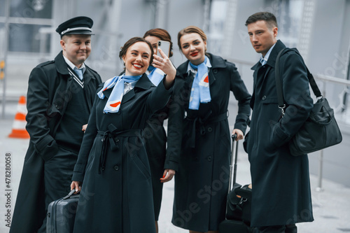 Aircraft crew in work uniform is together outdoors in the airport