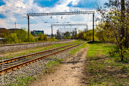 Railroad tracks with rails and electric power wires for trains. Rails and sleepers. High-voltage supply voltage wires. Railway equipment. Trains and locomotives. Direction of movement.