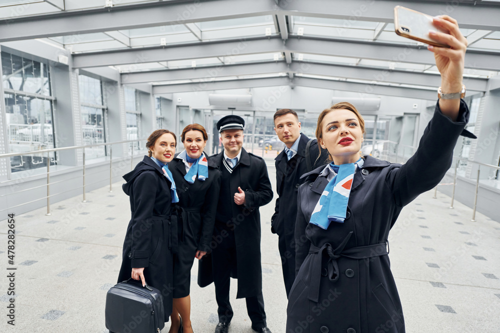 Doing selfie. Airplane crew in uniform is going to the work together