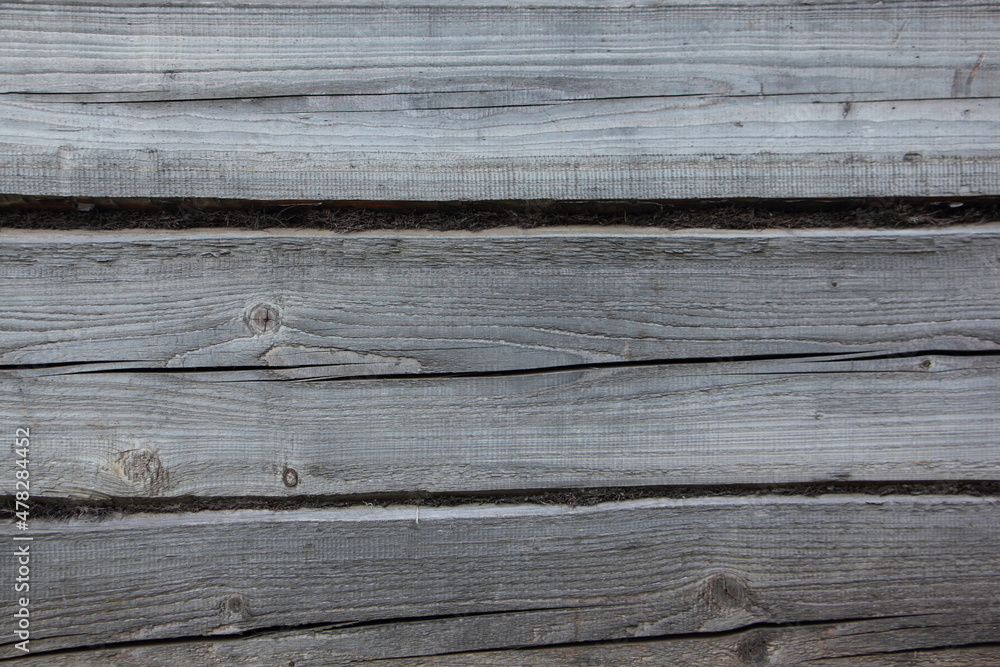 An old weathered horizontal wall of a log house with moss streaks of a rustic barn texture of a rural background An old weathered horizontal wall of a log house with moss streaks of a rustic barn texture of a rural background