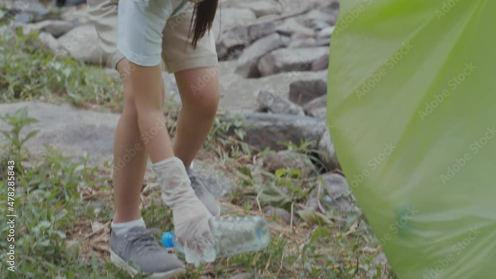 Close up of Volunteer Asian and girl Collecting plastic bottles into garbage bags. Activities aimed at instilling a sense of reverence for the natural world and the environment. slow motion Close up of Volunteer Asian and girl Collecting plastic bottles into garbage bags. Activities aimed at instilling a sense of reverence for the natural world and the environment. slow motion