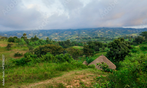 Breathtaking View to the Traditional African Houses, Green Trees and Mountains under Cloudy Blue Sky of the Omo River Valley, Ethiopia photo