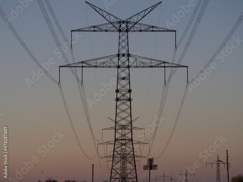 Strommast für Hochspannung mit Leitungen vor Abendrot