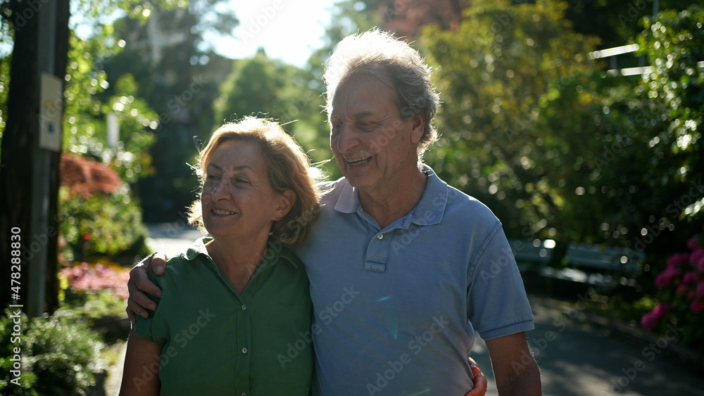 Two happy older people walking outside smiling, senior couple together in outdoor nature walk Two happy older people walking outside smiling, senior couple together in outdoor nature walk