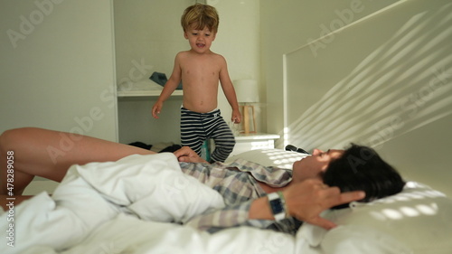 Tableau sur toile Son jumping on top of mother in the morning bed