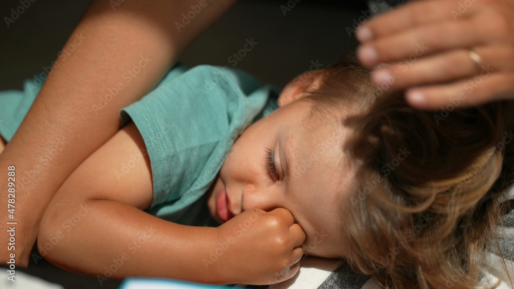 Fototapeta premium Sleepy child rubbing eye with hand, kid lying down resting