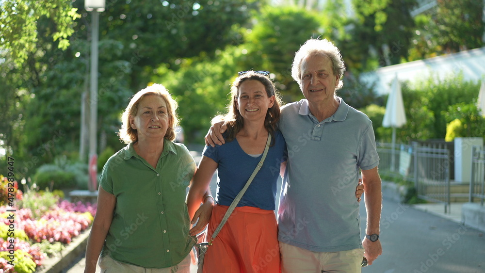 Naklejka premium Senior parents walking together with adult daughter outside talking in conversation