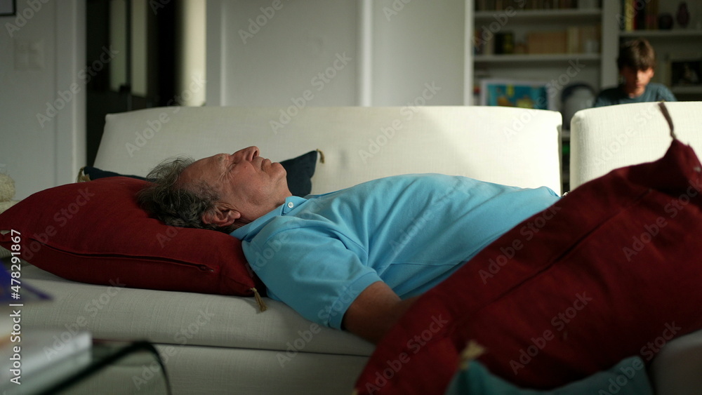 Obraz premium Older man lying in sofa resting. Senior person napping