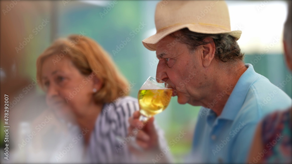 Older man drinking beer, candid senior drinks draft beer at restaurant Older man drinking beer, candid senior drinks draft beer at restaurant