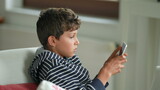 Little boy playing video-game indoors on tablet device