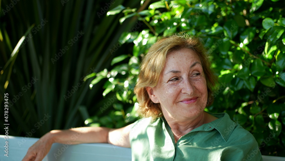 Happy senior woman sitting outside at park bench Happy senior woman sitting outside at park bench