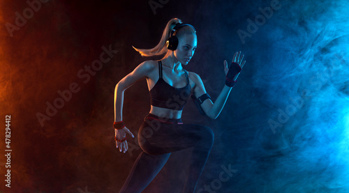 Sprinter run. Strong athletic woman running on black background wearing in the sportswear. Fitness and sport motivation. Runner concept. © Mike Orlov