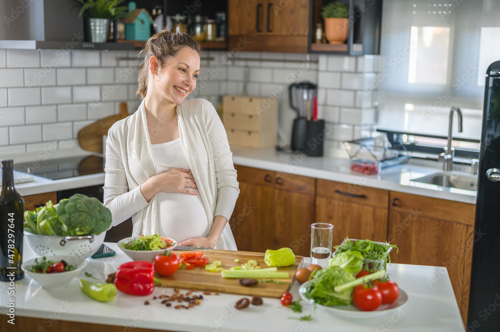 Young pregnant woman preparing healthy food with lots of vegetables at home kitchen Young pregnant woman preparing healthy food with lots of vegetables at home kitchen