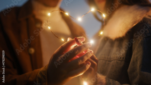 Coppia di ragazzo e ragazza si abbraccia in campagna di notte con striscia di luci led photo