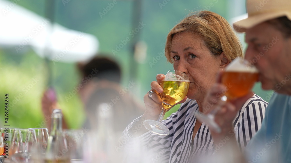 Fototapeta premium Candid older couple drinking beer. Senior woman drinks draft glass beer
