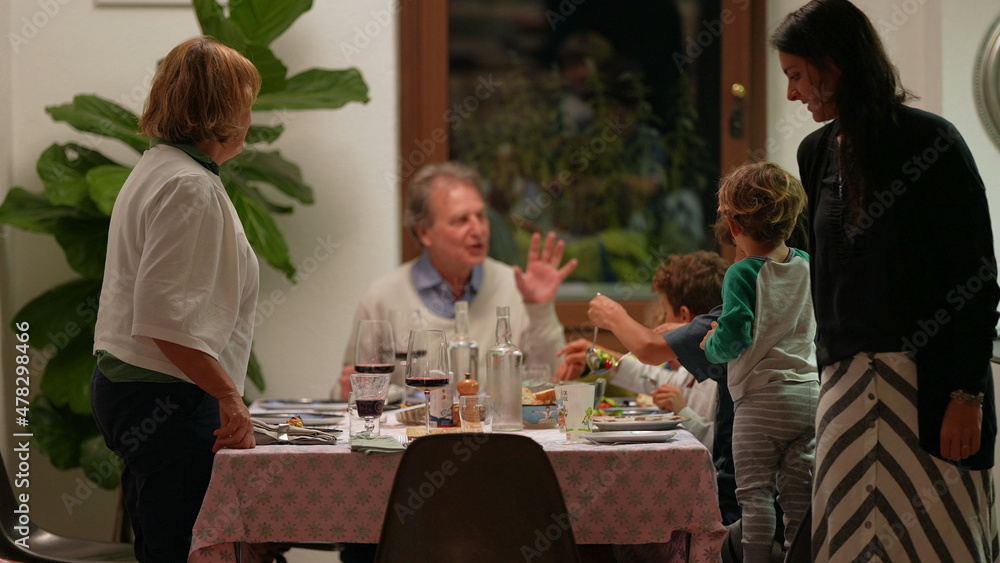 Candid family gathered around table celebrating holidays together Candid family gathered around table celebrating holidays together