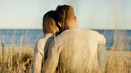Ragazza e ragazzo di spalle sulla spiaggia a San Valentino al tramonto photo