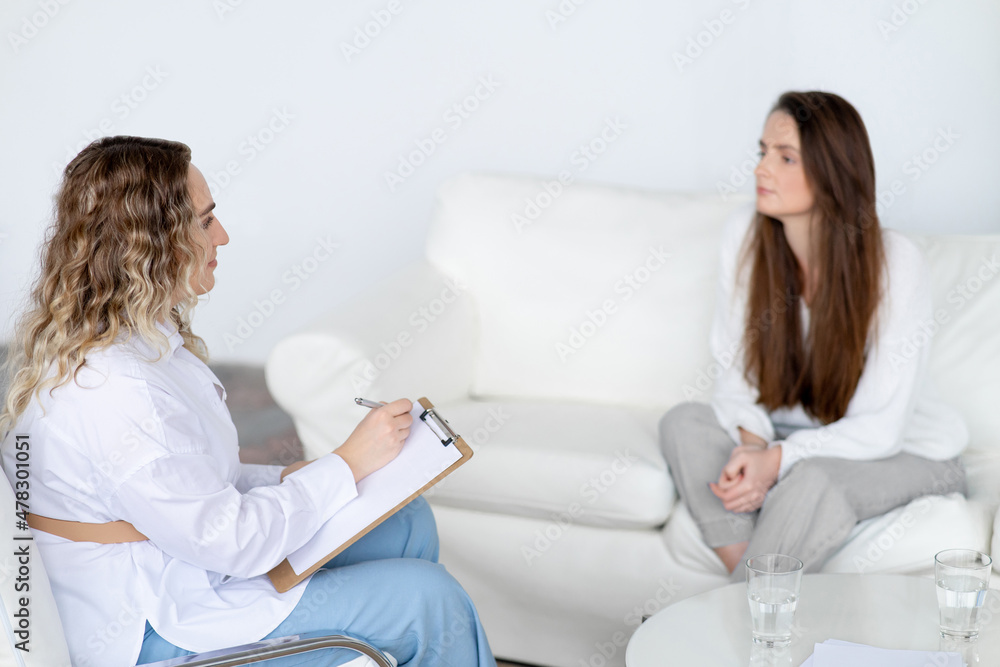 Consultation of a psychologist. A female doctor is talking to a patient in the office. Professional psychological assistance. There are glasses of water on the table. Consultation of a psychologist. A female doctor is talking to a patient in the office. Professional psychological assistance. There are glasses of water on the table.