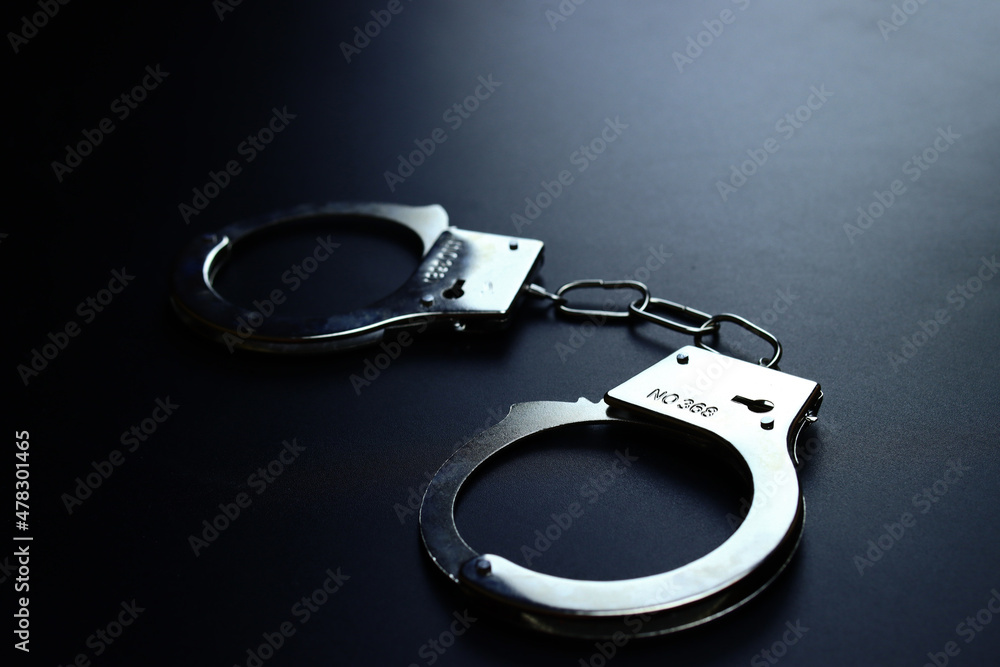 Police metal handcuffs on black background, crime fighting concept, selective focus Police metal handcuffs on black background, crime fighting concept, selective focus