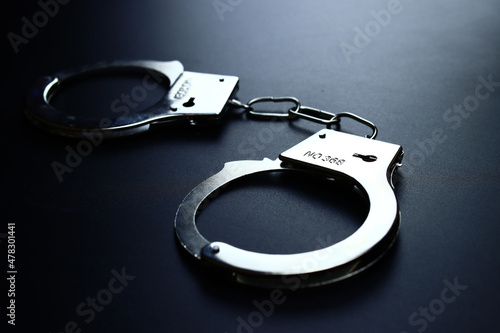 Police metal handcuffs on black background, close-up, selective focus