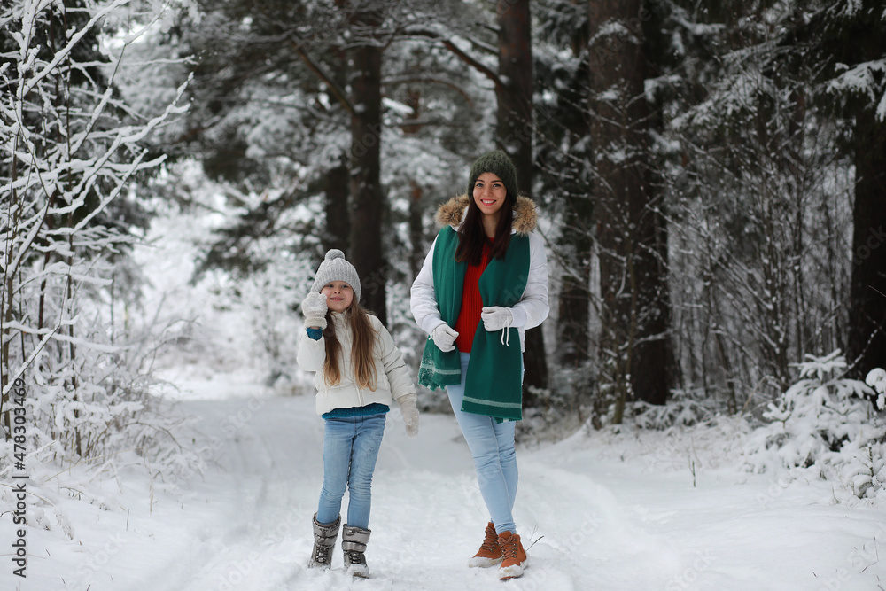 Young family for a walk. Mom and daughter are walking in a winter park.