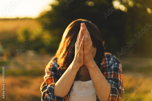 Valokuva Young woman closed her eyes, praying in a field during beautiful sunset