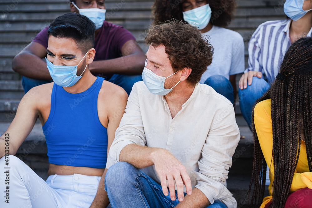 Obraz premium Young diverse people laughing together wearing safety mask outdoor in the city - Focus on center man face