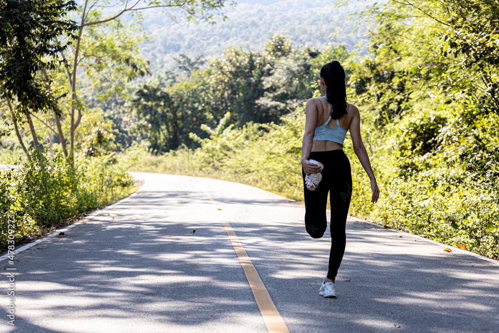 Fototapeta premium An Asian woman warming up before running, she is jogging in a park where many people come for morning and evening jogging, running is another popular activity. Health care concept with jogging.