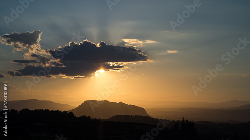 Glorious light and sun rays as the sun peeps from behind a cloud just before sunset over hills and valleys of spain valenciana