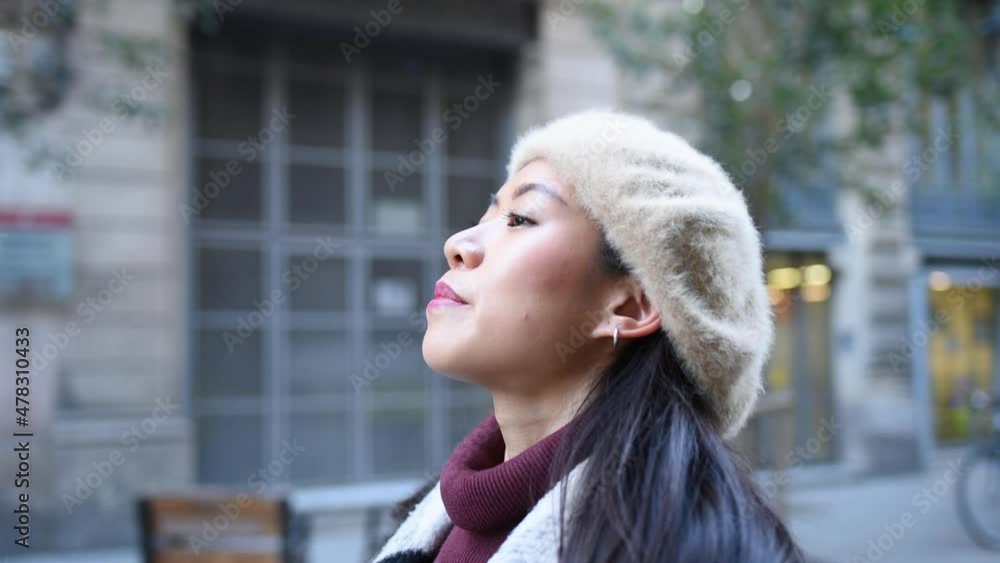 Chinese female in stylish beret taking off face mask then closing eyes and breathing while standing on city street during pandemic. Concept of pandemic end Chinese female in stylish beret taking off face mask then closing eyes and breathing while standing on city street during pandemic. Concept of pandemic end