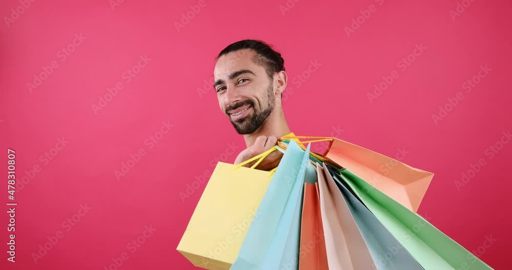 Profile of happy man carrying his shopping bags over pink background Profile of happy man carrying his shopping bags over pink background