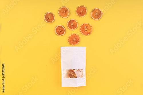 dried orange slices coming out of a bag on a yellow background