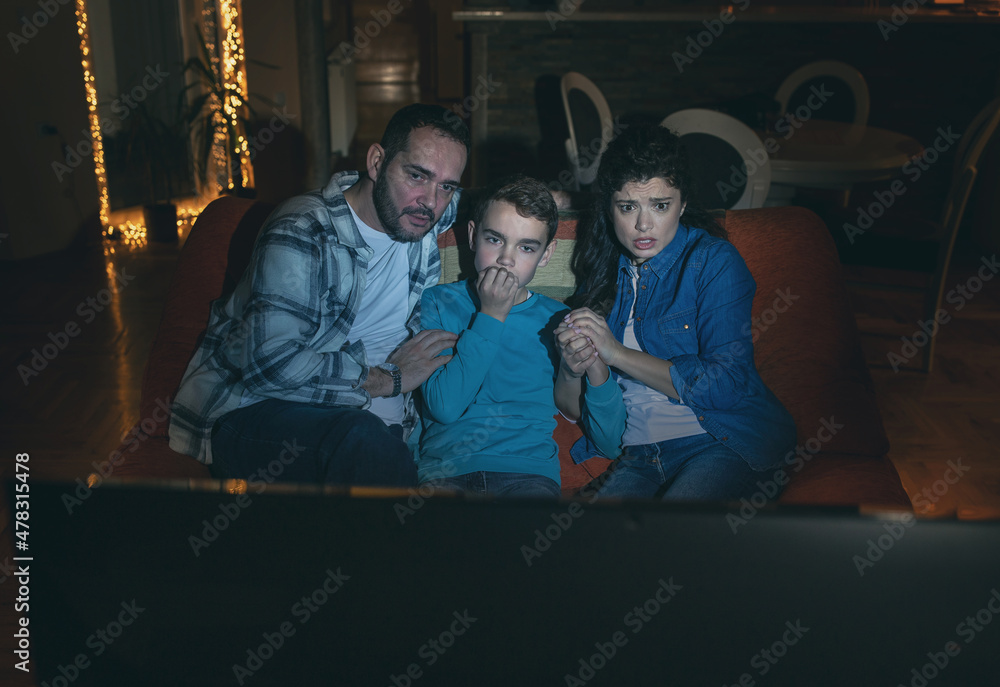 Obraz premium Father, mother and son looking horror movie at home