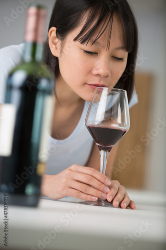 young woman smelling red wine in a glass