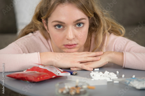 Fotografie girl behind table covered with hand rolling cigarette paraphernalia