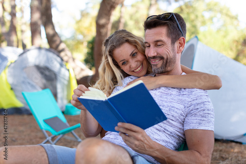 young couple sitting by the camp and reading © auremar