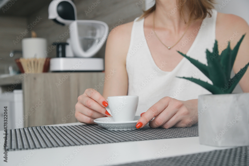 Young woman sitting at the kitchen table and enjoying her morning coffee Young woman sitting at the kitchen table and enjoying her morning coffee
