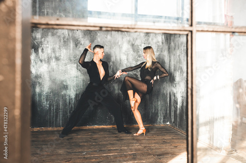 Couple of two professional ballroom dancers is dancing on loft studio. Beautiful art performance. Sport life concept. Passion and emotional dance.