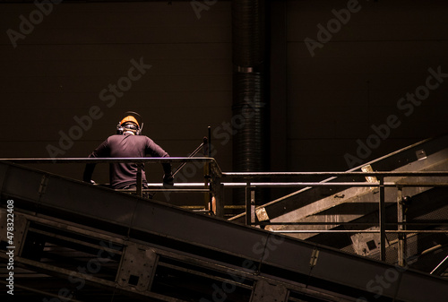 Industry worker with hard hat overseeing the operations at a recycling centre.