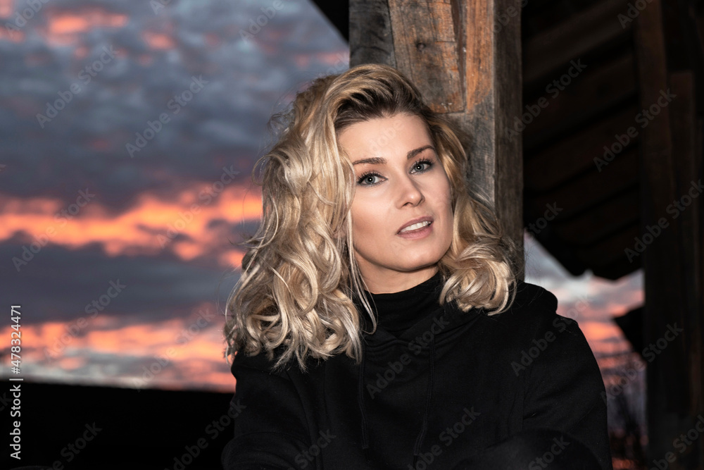 portrait of beautiful blonde woman outdoors at sunset sitting