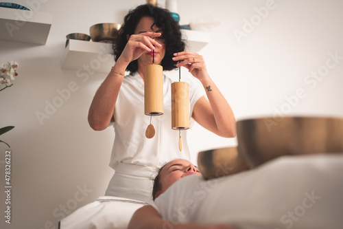 Fotografi Caucasian female therapist  holding Koshi chime musical  instrument over young w