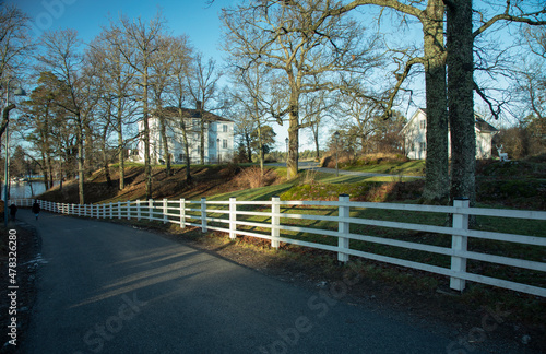 White wooden fence along the road and white stone houses against the blue winter sky