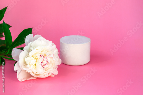 Empty white podium mockup with white peony on pink pastel background closeup