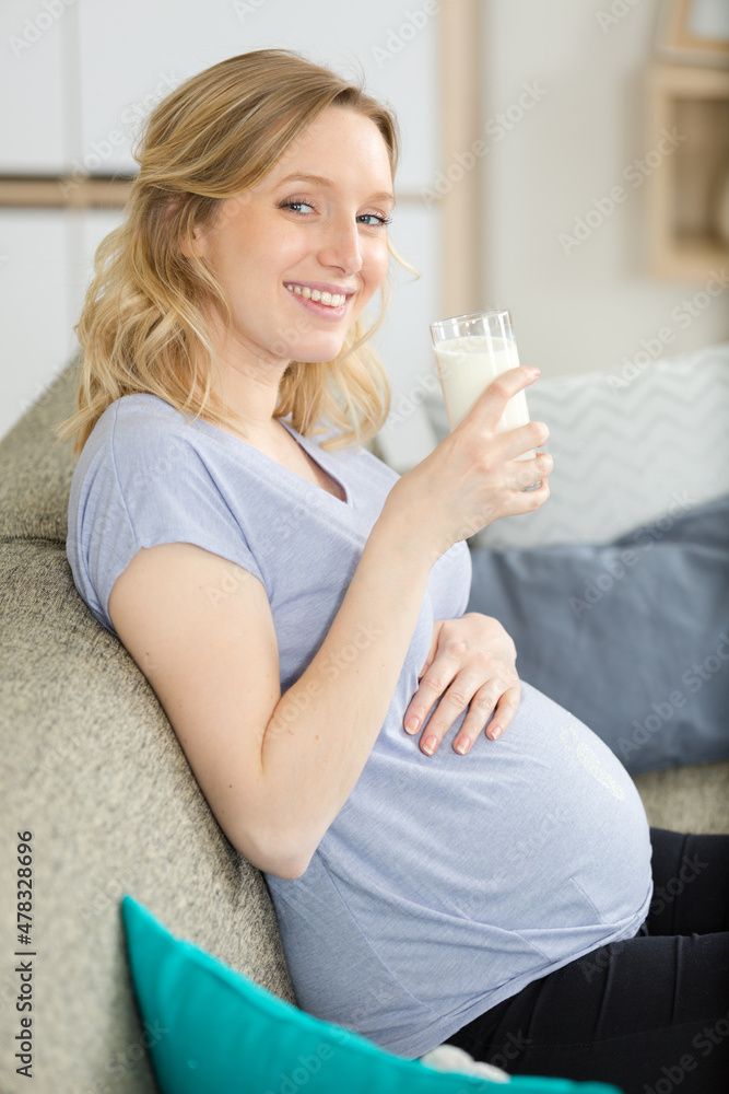 young pregnant woman with milk and breakfast on sofa young pregnant woman with milk and breakfast on sofa