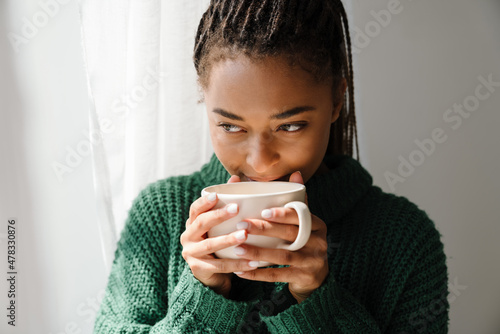 Young black woman with pigtails drinking tea at home