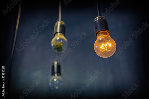Glass dusty light bulb in a vintage base hanging on an electrical wire