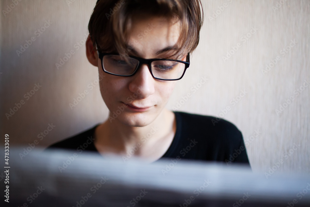 Young man reading a newspaper with emotions on his face Young man reading a newspaper with emotions on his face