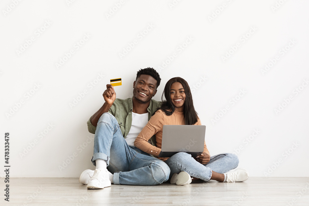 Emotional african american couple using laptop and credit card Emotional african american couple using laptop and credit card