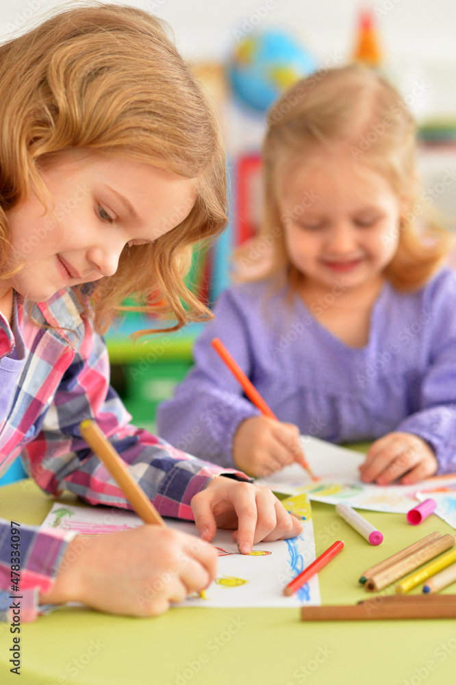 Cute little girls sitting at table and drawing Cute little girls sitting at table and drawing