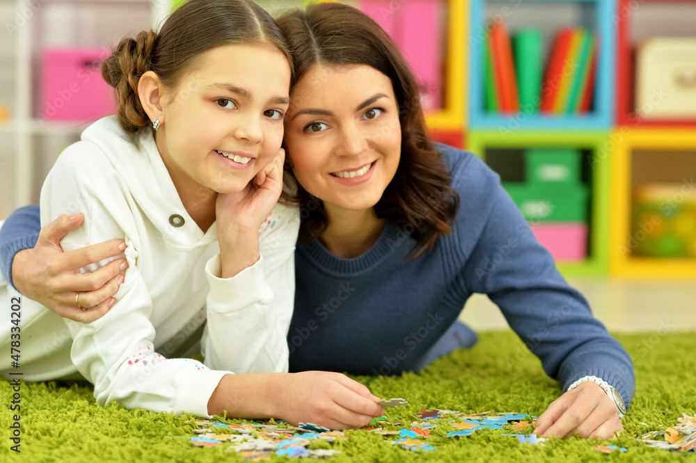 Portrait of mother with little daughter collecting puzzles Portrait of mother with little daughter collecting puzzles
